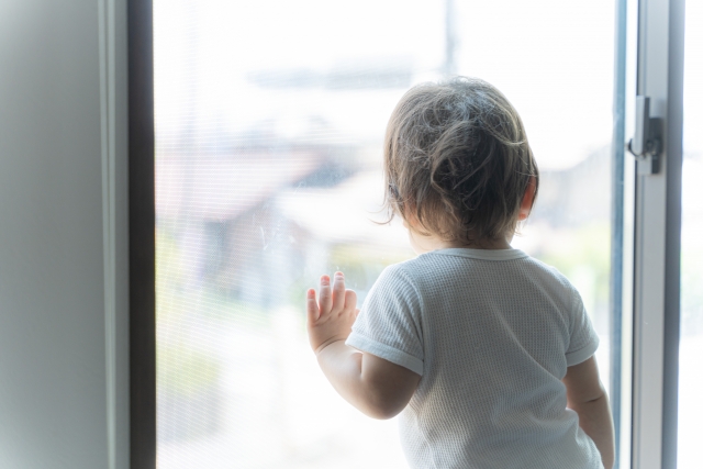 窓から外を眺める子供